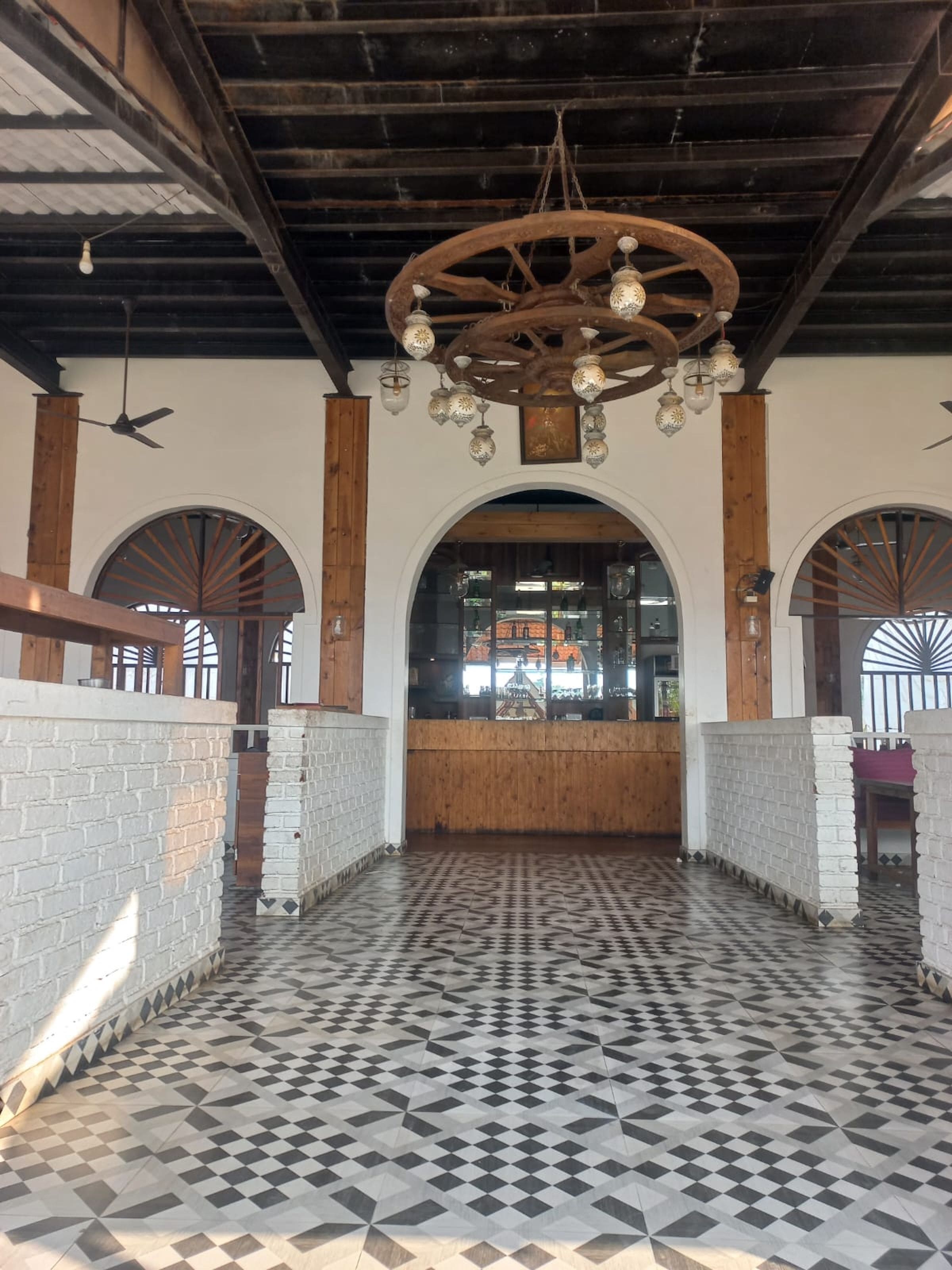 Un vaste hall doté d’un sol à motifs, de poutres en bois et d’une porte d’entrée centrale en arc de cercle.