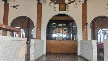 Un vaste hall doté d’un sol à motifs, de poutres en bois et d’une porte d’entrée centrale en arc de cercle.