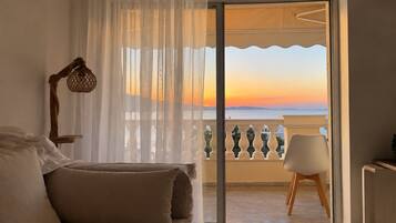 A bedroom with a balcony, a bed with pillows, a chair, and a lamp.