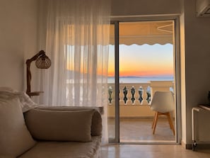 A bedroom with a balcony, a bed with pillows, a chair, and a lamp. - Athens Riviera Sea View - Piraeus (Pireas)