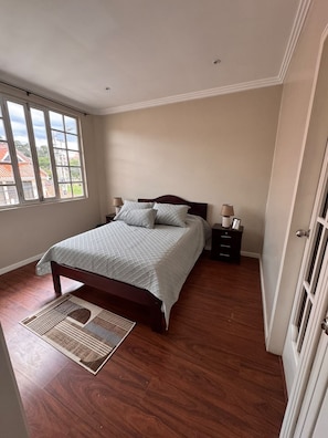 Une chambre à coucher avec un lit, des tables de chevet, une lampe et une fenêtre.