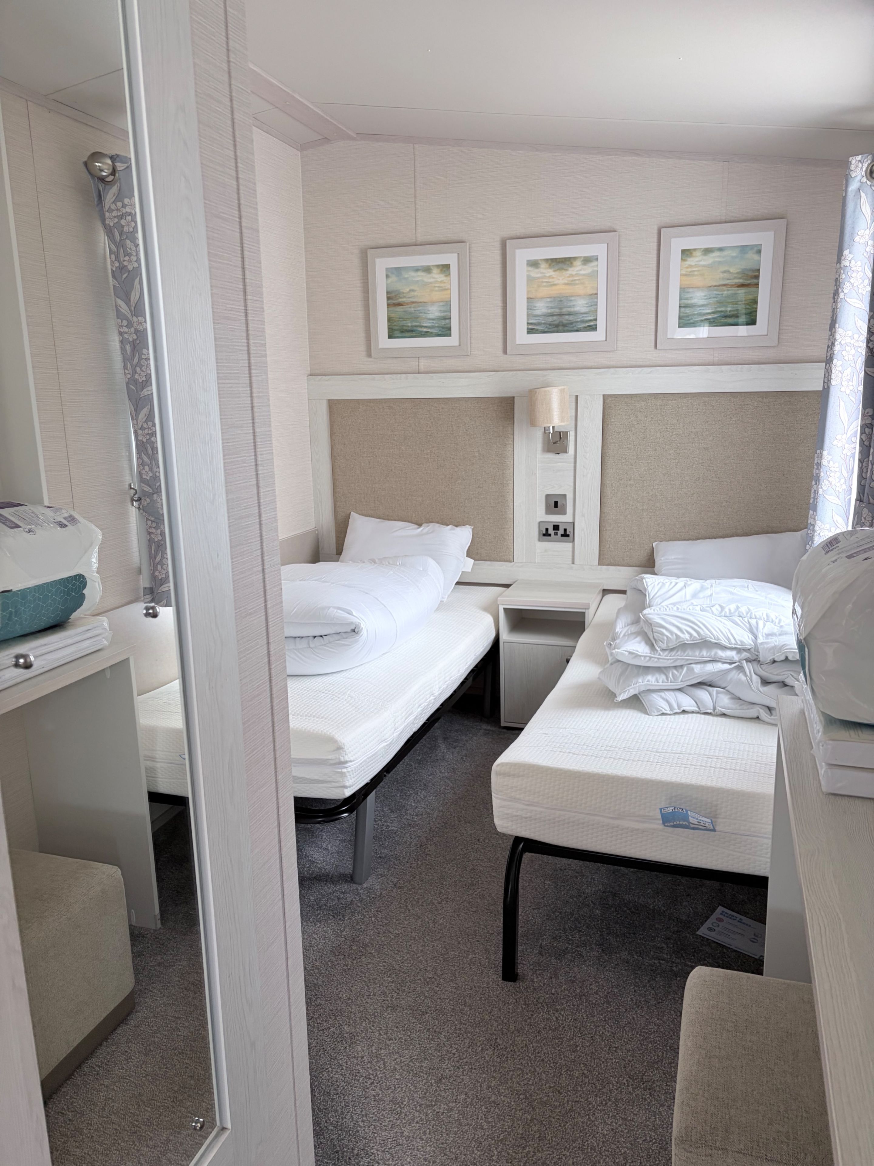 Een hotelkamer met twee bedden, een nachtkastje, een lamp en een schilderij aan de muur.