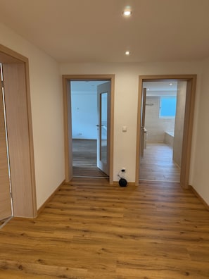 A hallway with wooden flooring leading to a room with a window. - New Listing (Lonnerstadt)