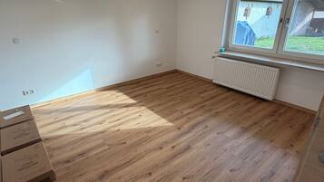Une pièce avec un plancher en bois, une fenêtre donnant sur un paysage agréable et plusieurs cartons.
