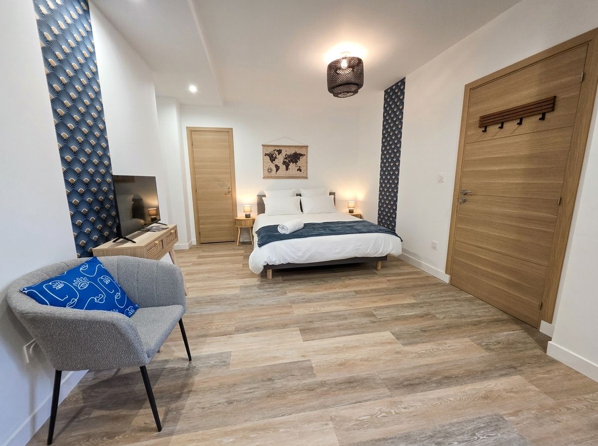 A bedroom with a bed, a chair, a wardrobe, a television, and a world map on the wall.