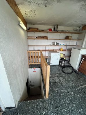 Cuina amb rentadora, aspiradora i prestatges de fusta.