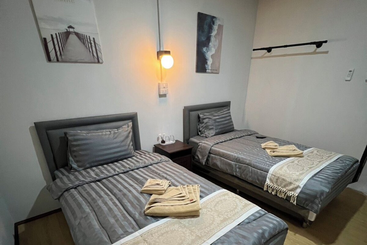 A room with two beds, a wall-mounted light, and a poster.