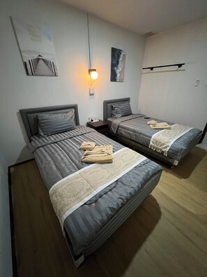 A room with two beds, a wall-mounted light, and a poster. - SONGTHAI Muay Thai (Muang Krabi)