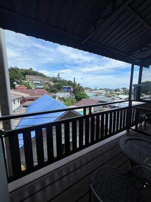 A balcony with a view of a residential area, including houses with blue roofs and a clear sky. - SONGTHAI Muay Thai (Muang Krabi)