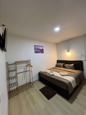 A bedroom with a bed, a wall-mounted TV, a picture, and a light fixture. - SONGTHAI Muay Thai (Muang Krabi)