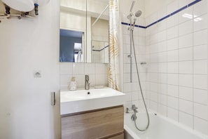 Ein Badezimmer mit Waschbecken, Spiegel, Dusche und einem Holzschrank.