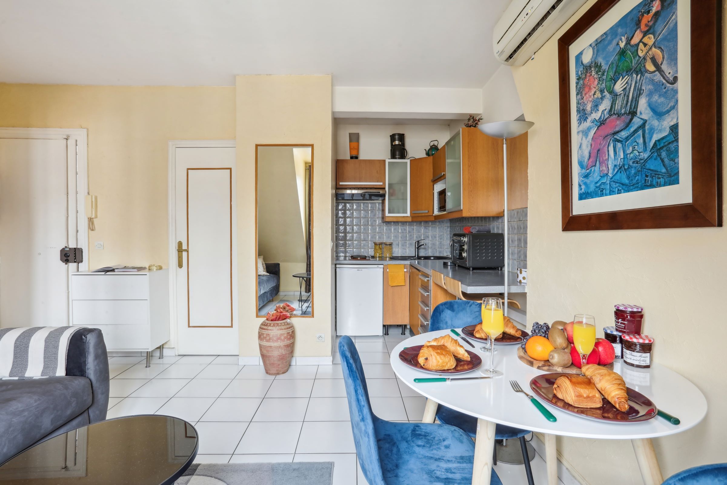 Ein modernes Wohnzimmer mit Essbereich, einer Küche im Hintergrund und einem großen Gemälde an der Wand.