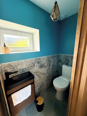 Une salle de bain avec des toilettes, un lavabo avec une serviette et une fenêtre.