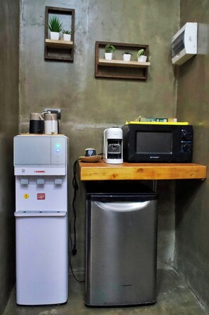 Een kitchenette met een koffiezetapparaat, magnetron en koelkast.
