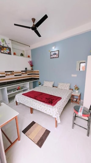 Une chambre à coucher comprenant un lit, un bureau, une chaise, un ventilateur de plafond et une commode.