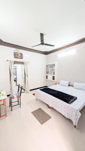 Une chambre à coucher avec un lit, un ventilateur de plafond, un bureau et une chaise.
