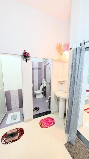 Une salle de bain comprenant des toilettes, un lavabo et un espace douche.