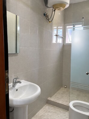 A bathroom with a sink, a toilet, and a shower area. - Alpines Hotels and Reservations (Port Harcourt)
