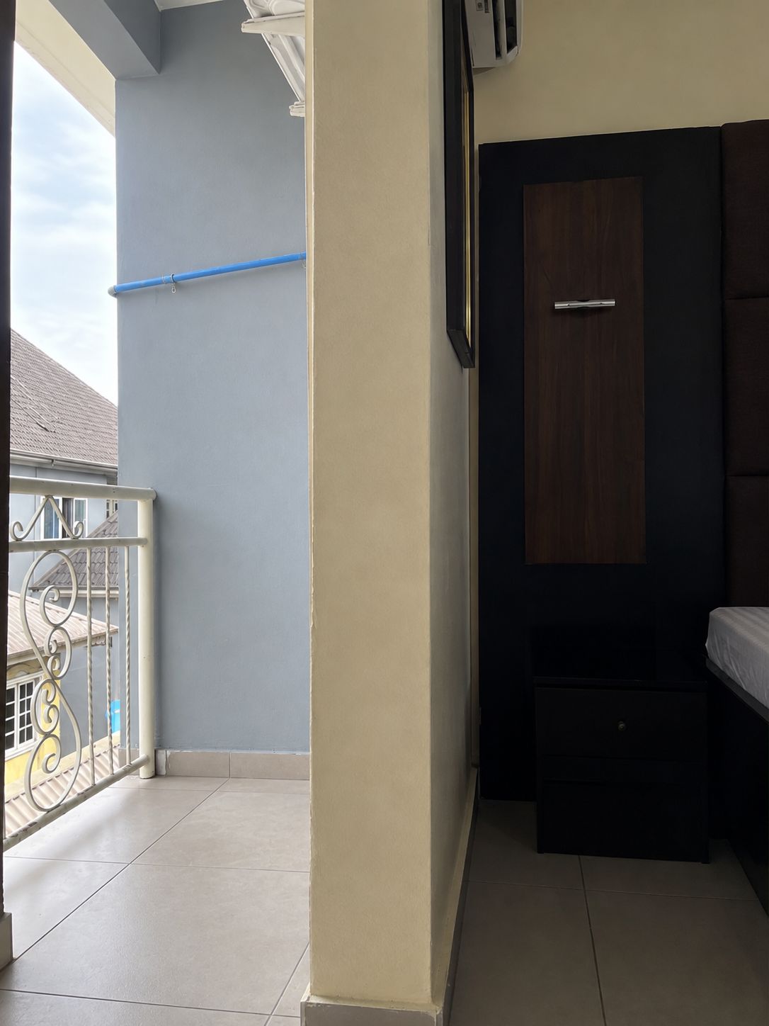 Una habitación con cama, armario y un mueble pequeño. Tiene un balcón con barandilla y vistas al exterior.
