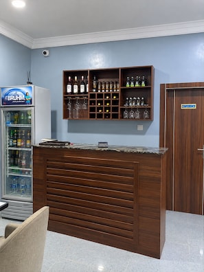 A bar area with a wooden counter, a refrigerator stocked with beverages, and a sign indicating a conference room. - Alpines Hotels and Reservations (Port Harcourt)