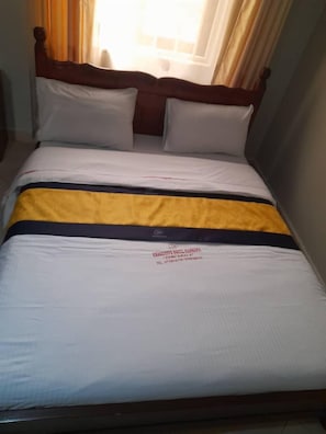 Un letto con testiera in legno, biancheria bianca e coperta a righe gialle e nere.