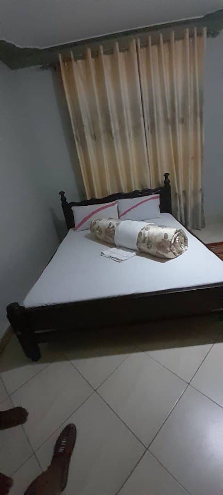 A bed with a white mattress and a rolled-up blanket, a pillow, and a bedside table with a lamp.