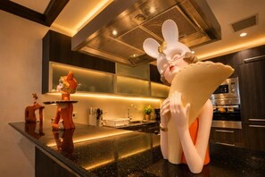 Una cocina moderna con encimera negra, electrodomésticos de acero inoxidable y figuritas decorativas.