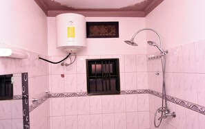 Un bagno con piastrelle rosa, una doccia, un water e uno scaldabagno.