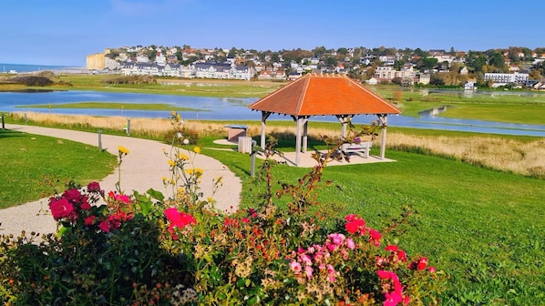 A gazebo in a park with a pathway and flowers in the foreground. - New Listing (Petit-Caux)
