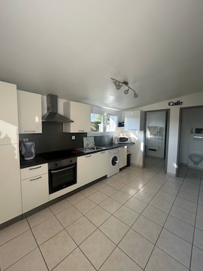 A modern kitchen with white cabinets, a black countertop, a built-in oven, a microwave, and a washing machine. - New Listing (Petit-Caux)