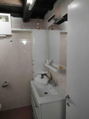 A compact bathroom with a white sink, mirror, and storage cabinets. - New Listing (Comacchio)