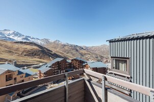 Ein Berglodge mit mehreren Holzhäusern, einem Balkon und Blick auf schneebedeckte Berge.