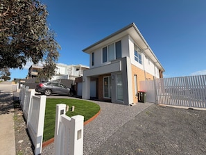 Ein modernes, zweistöckiges Haus mit Garage, Auffahrt und weißem Zaun.