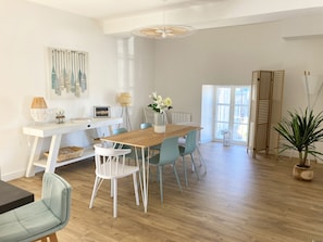 Un espace repas moderne avec une table en bois, des chaises blanches et un vase de fleurs.
