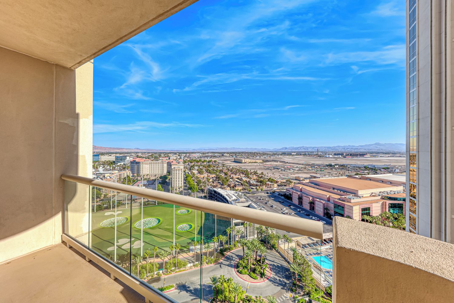 A balcony with a clear view of a cityscape, including buildings and a sports field.