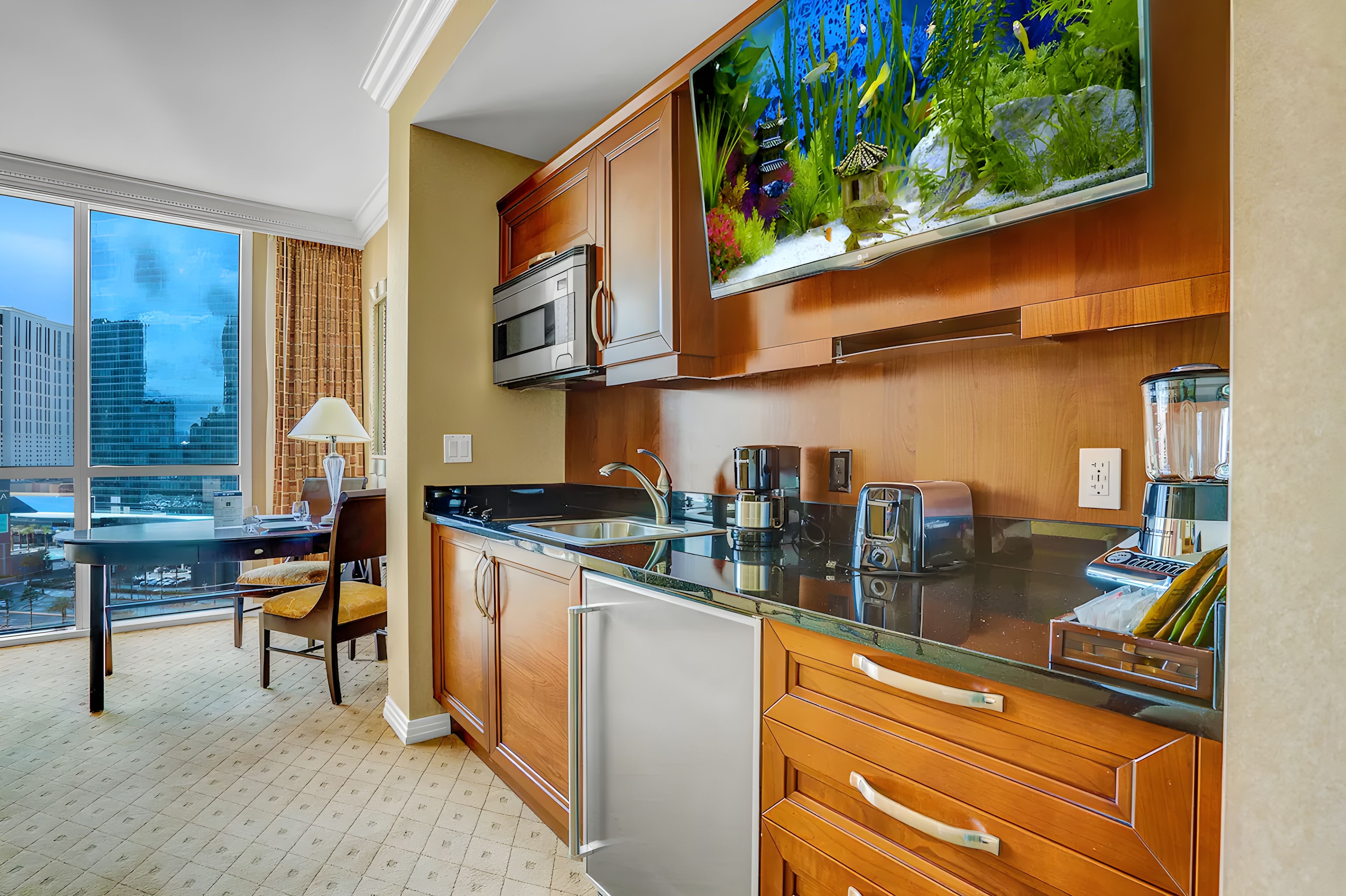 A modern kitchen with a large window, a microwave, a sink, and a refrigerator.