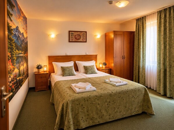 Habitación de hotel con una cama grande, dos mesitas de noche, un armario de madera, un cuadro en la pared y una ventana con cortinas.