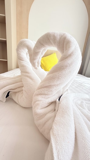 Een witte handdoek rond een bed met een geel kussen.
