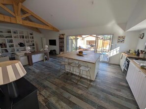 A spacious kitchen with a central island, wooden beams, and a view to the outside. - New Listing (Gujan-Mestras)