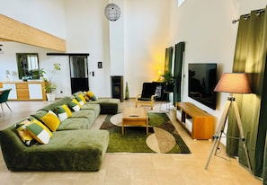 Amplia sala de estar con sofá modular, mesa de centro, televisor y un cuadro en la pared.