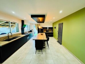 Una cocina moderna con una isla central, comedor y vistas al exterior.