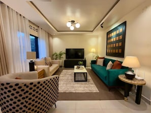 Una sala de estar moderna con un sofá, un sillón, una mesa de centro y un televisor.