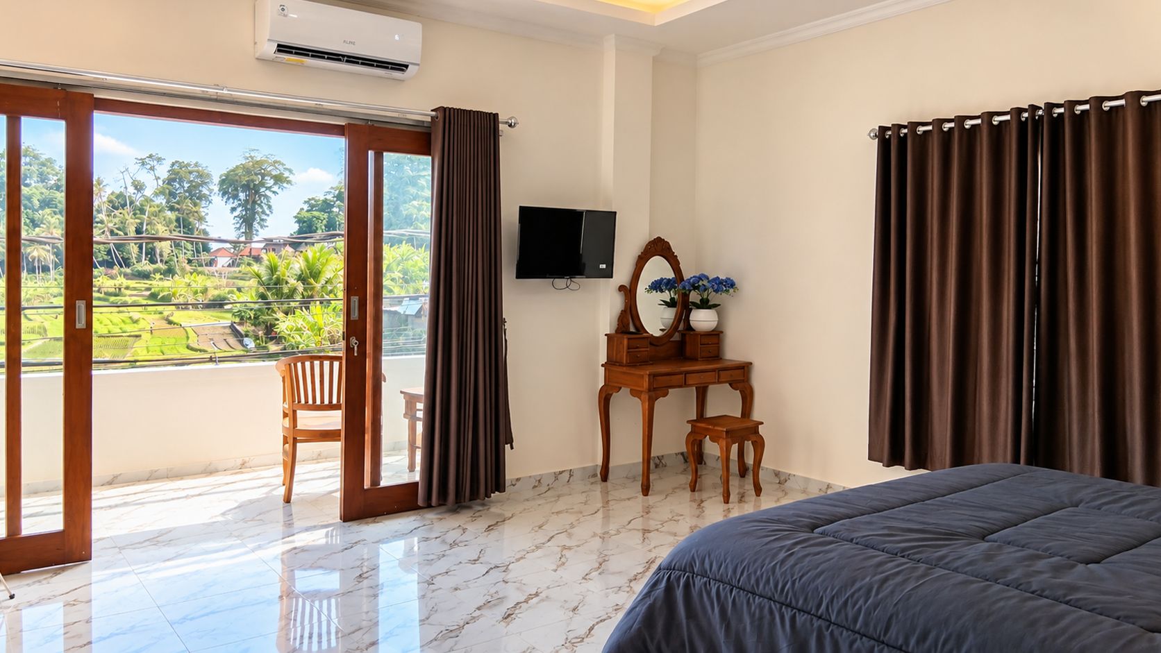 A hotel room with a bed, a desk with a mirror, a chair, and a television.