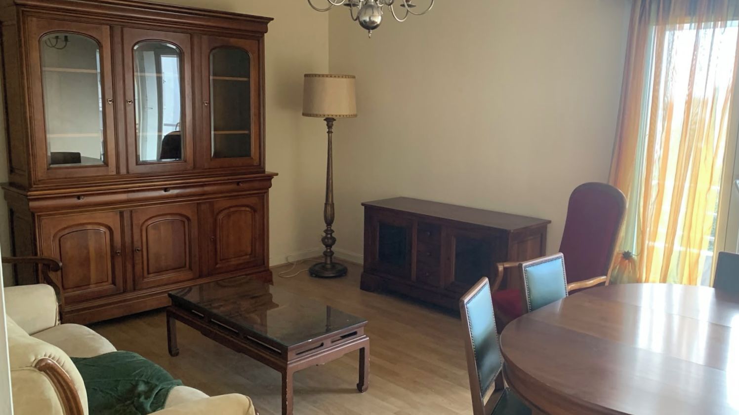 Una sala de estar con un aparador de madera, una mesa, un sofá y una lámpara.