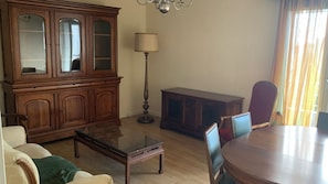 A living room with a wooden cabinet, a table, a sofa, and a lamp. - New Listing (Brive-la-Gaillarde)