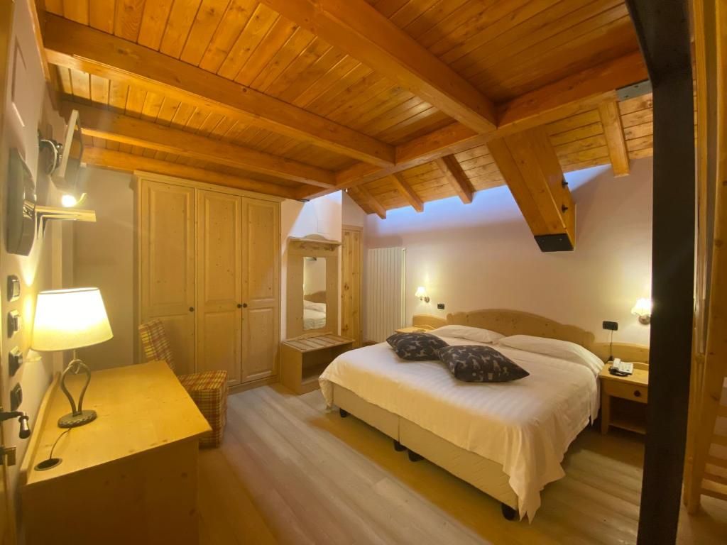 Un dormitorio con techo de madera, una cama con almohadas, una mesita de noche con lámpara y un armario.
