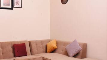 A beige sectional sofa with three cushions in red, yellow, and purple, a wooden coffee table, and three wall-mounted circular decorations.