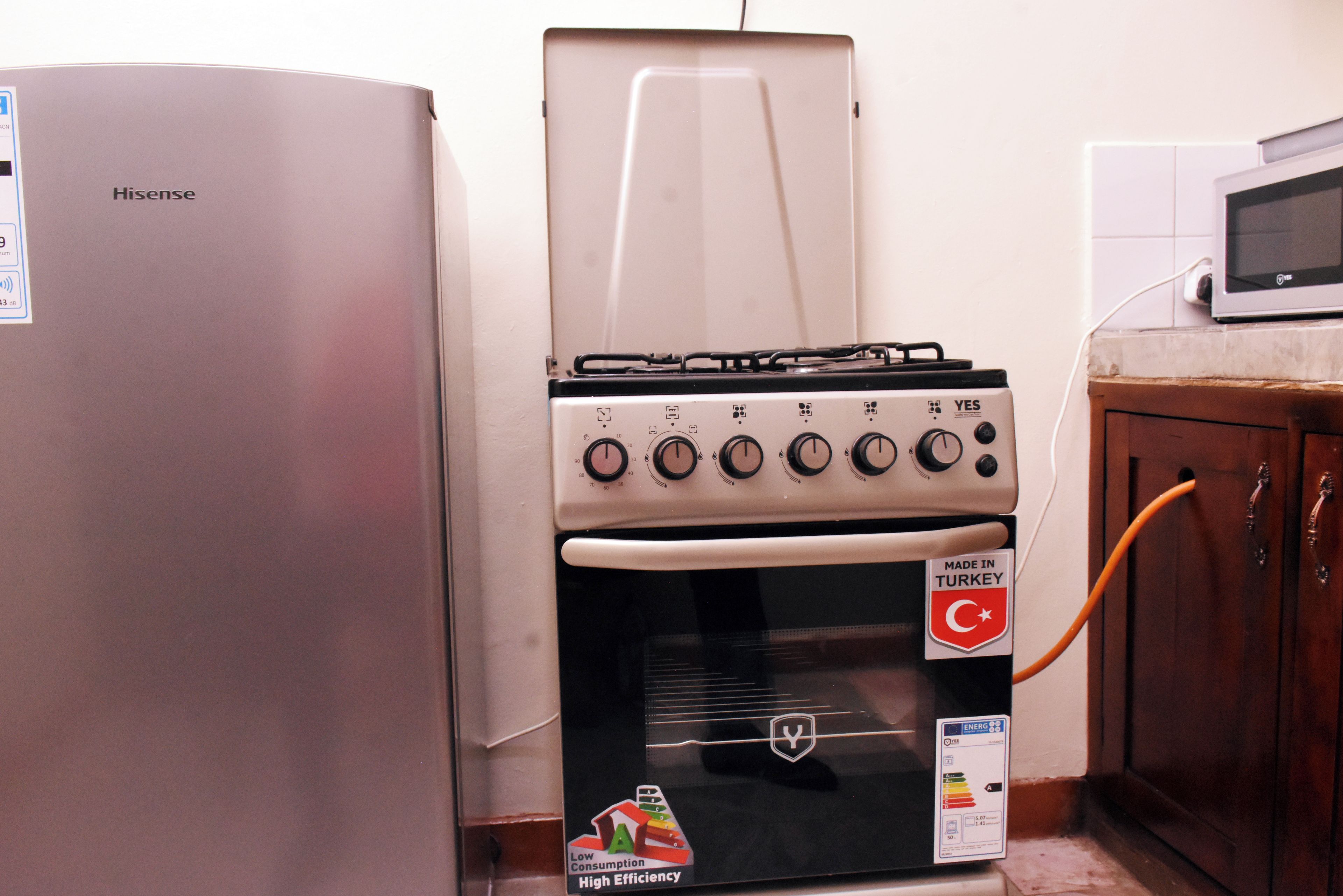 A kitchen with a Hisense refrigerator, a Yes brand gas stove, and an oven.