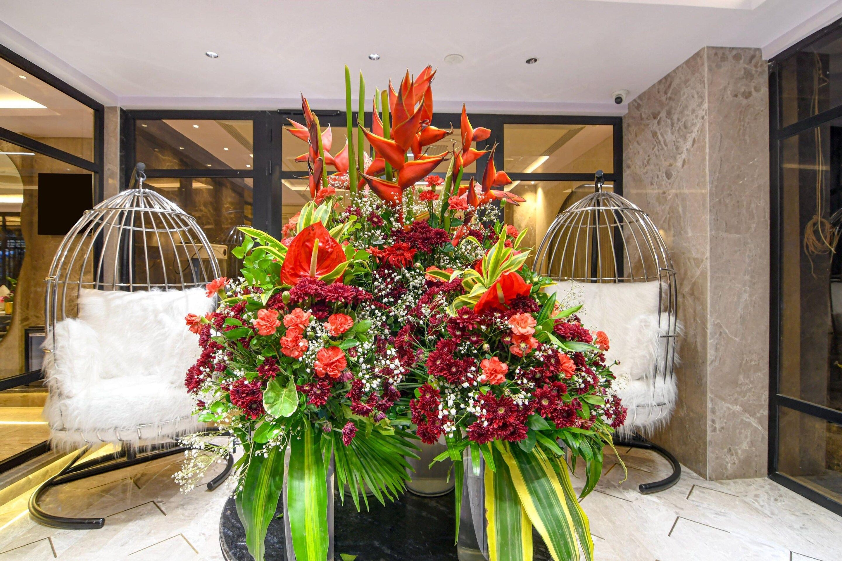A floral arrangement in a lobby with a modern interior design, including a glass partition and a white fur-covered bench.