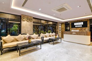A hotel lobby with a reception desk, a sofa, and a coffee table. - Deluxe Room Alamin International (Kolkata)